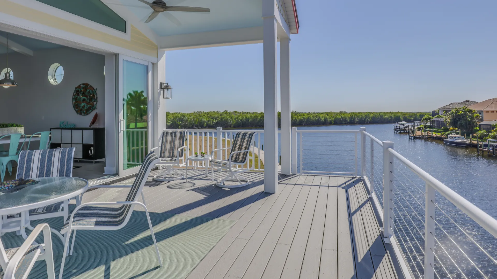 Balcony with lounge chairs and a glass table overlooking a waterway.