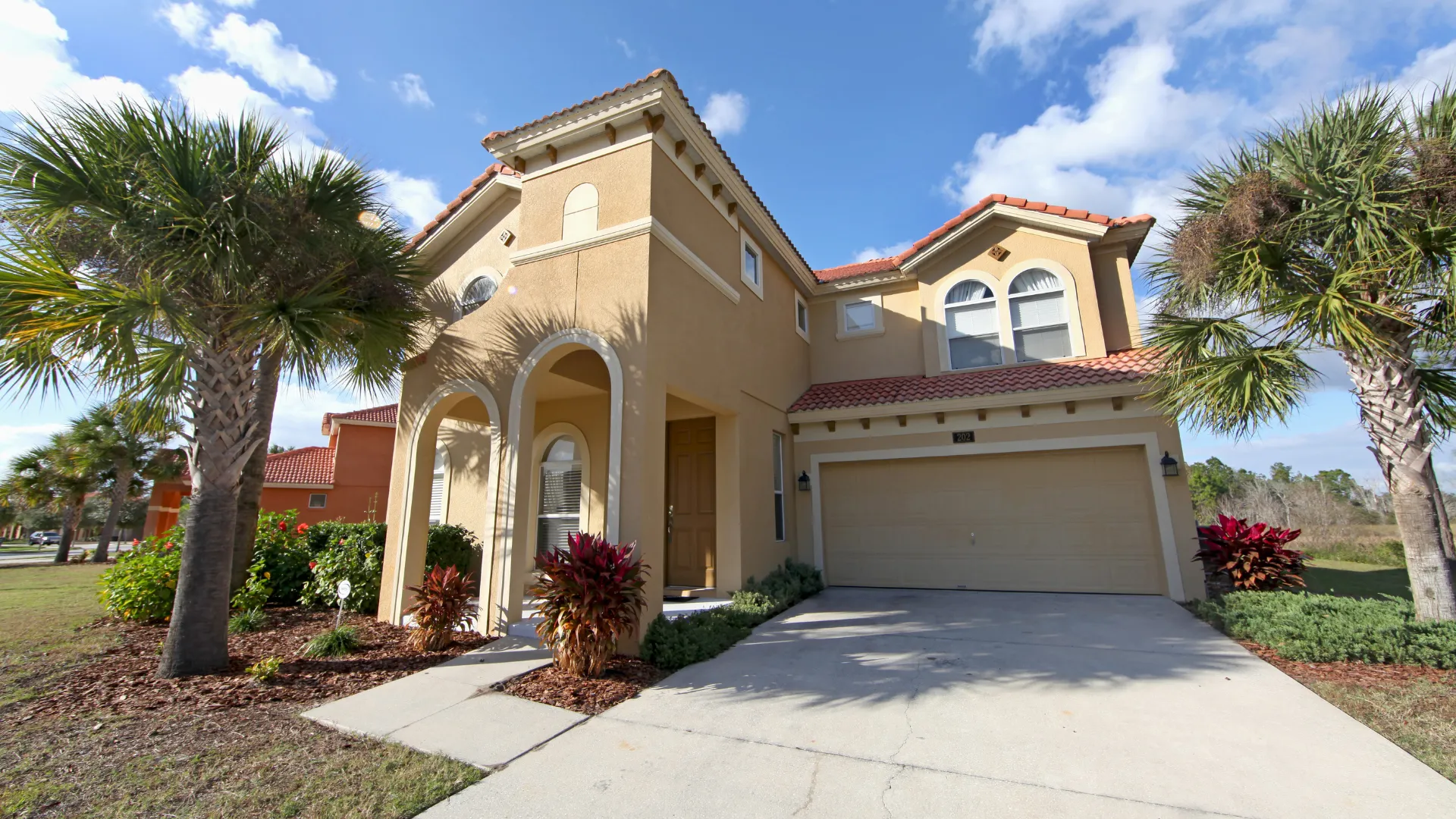 California real estate house with two floors, palm trees, and a driveway.
