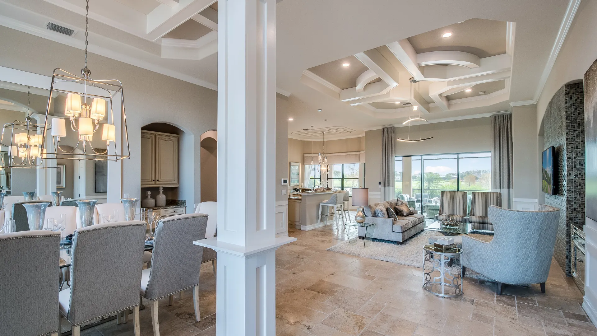 Living area with dining space, kitchen, seating, large windows, and tile floor.