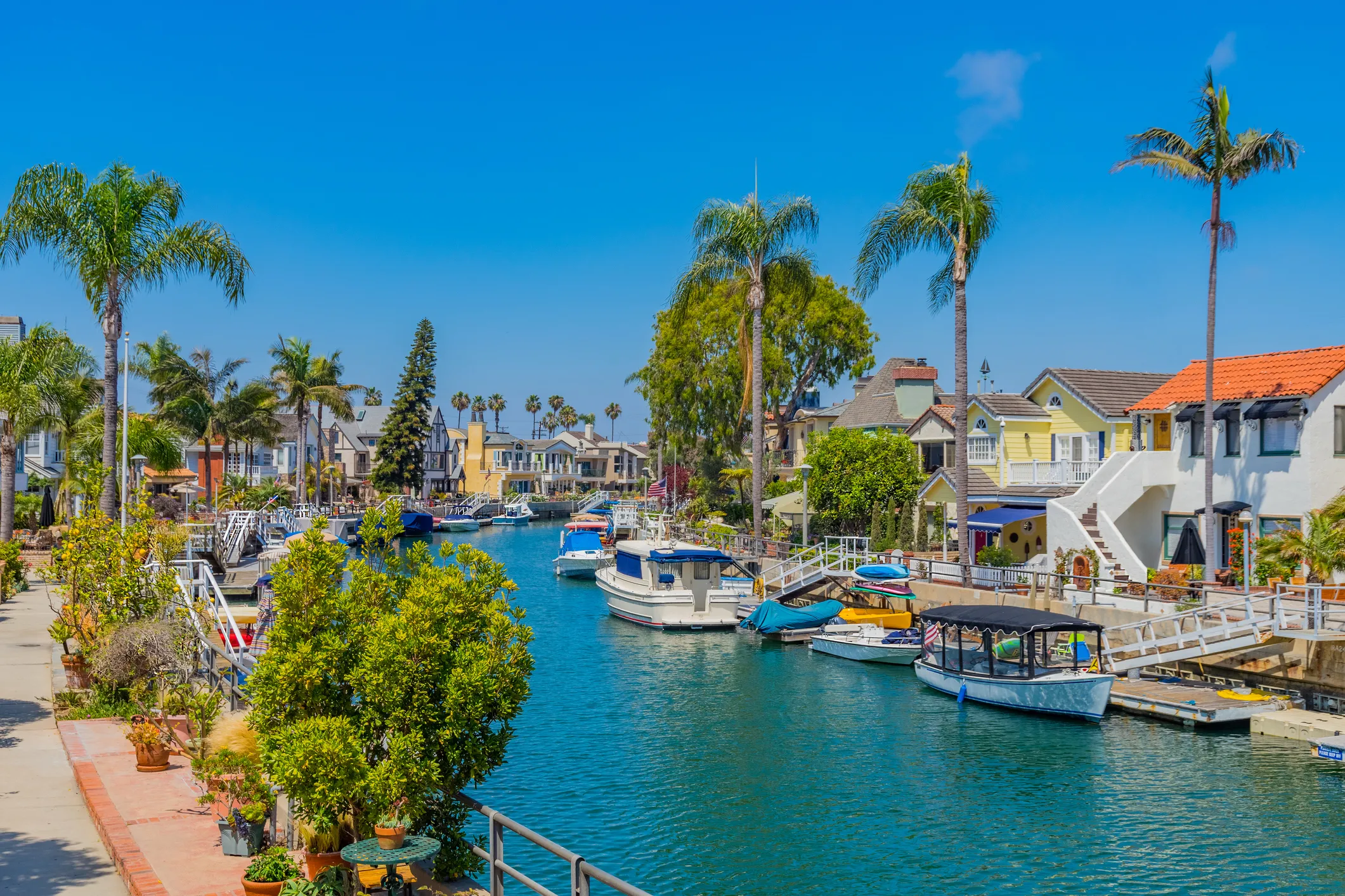 Canal with boats, palm trees, and colorful California real estate houses.