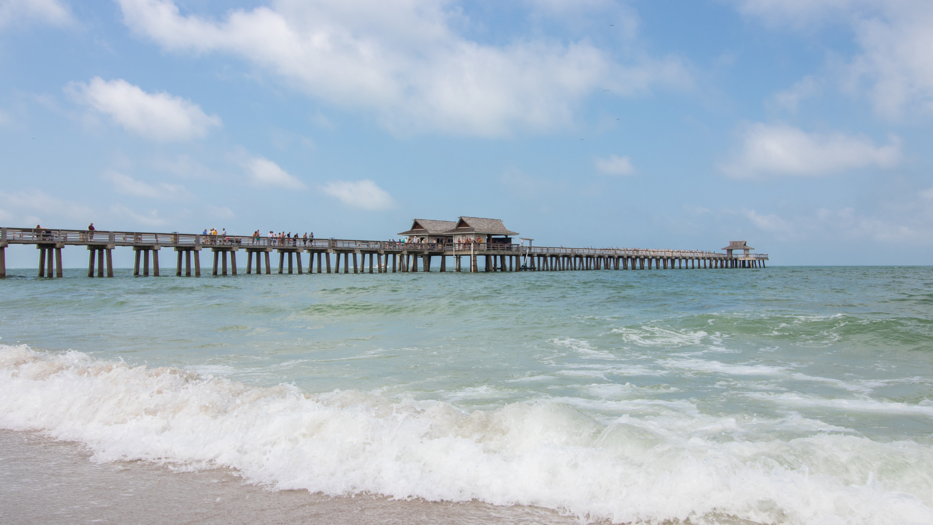 Long wooden pier over the ocean with waves and ocean view.